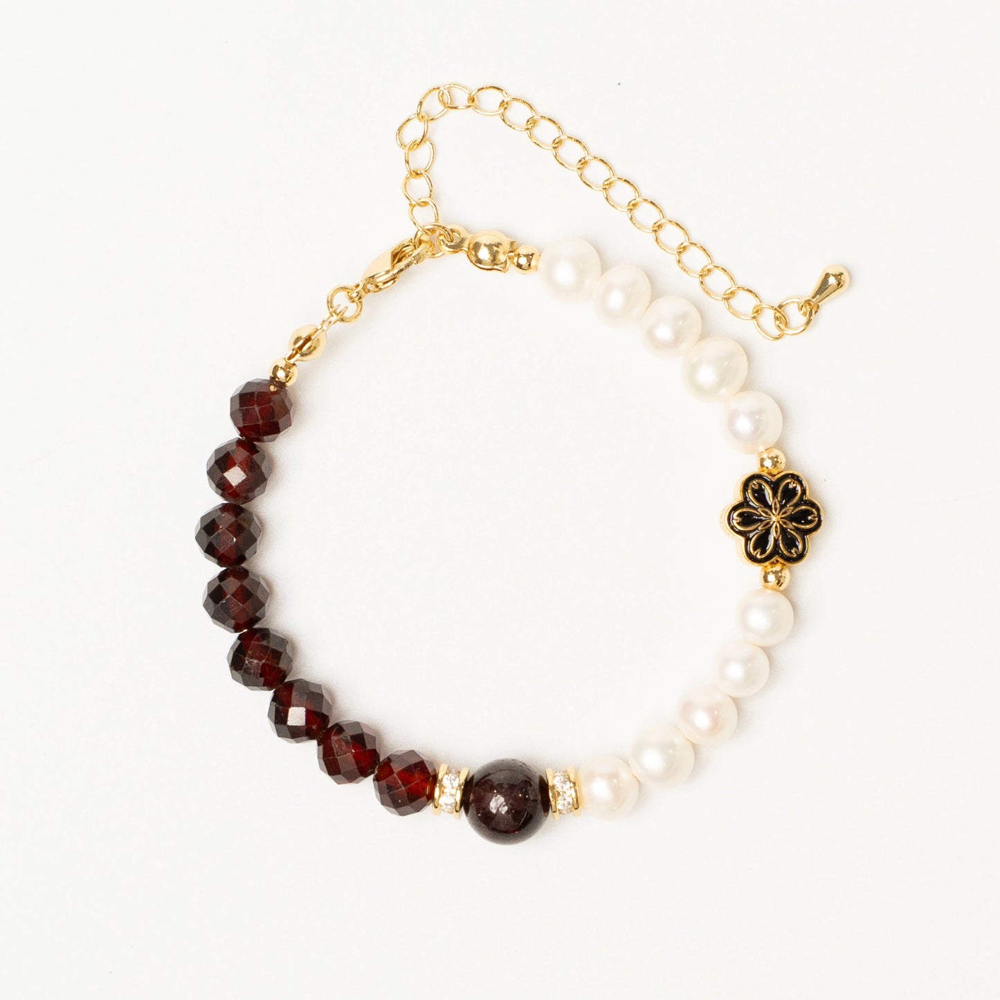 Close-up detail of the Mulstio bracelet showing the deep red garnet bead and smooth white pearl, hand-strung on a delicate gold-filled chain.