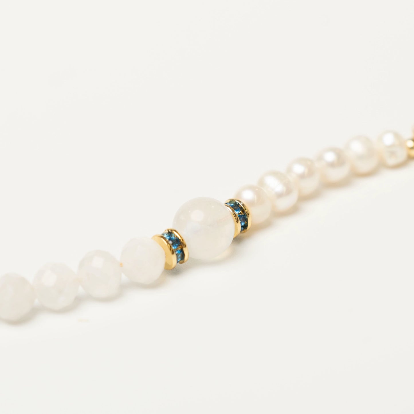 Close-up of the elegant bracelet, showcasing the ethereal blue sheen of the Moonstone bead next to the luminous glow of the Pearl, creating a soft, magical aesthetic.