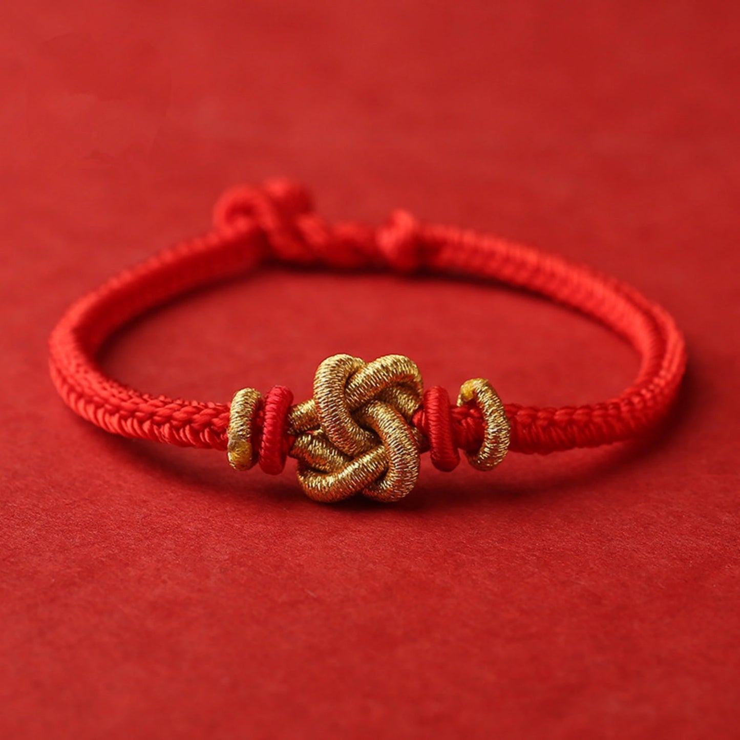 Close-up detail of handcrafted red thread bracelet showing golden wire craftsmanship