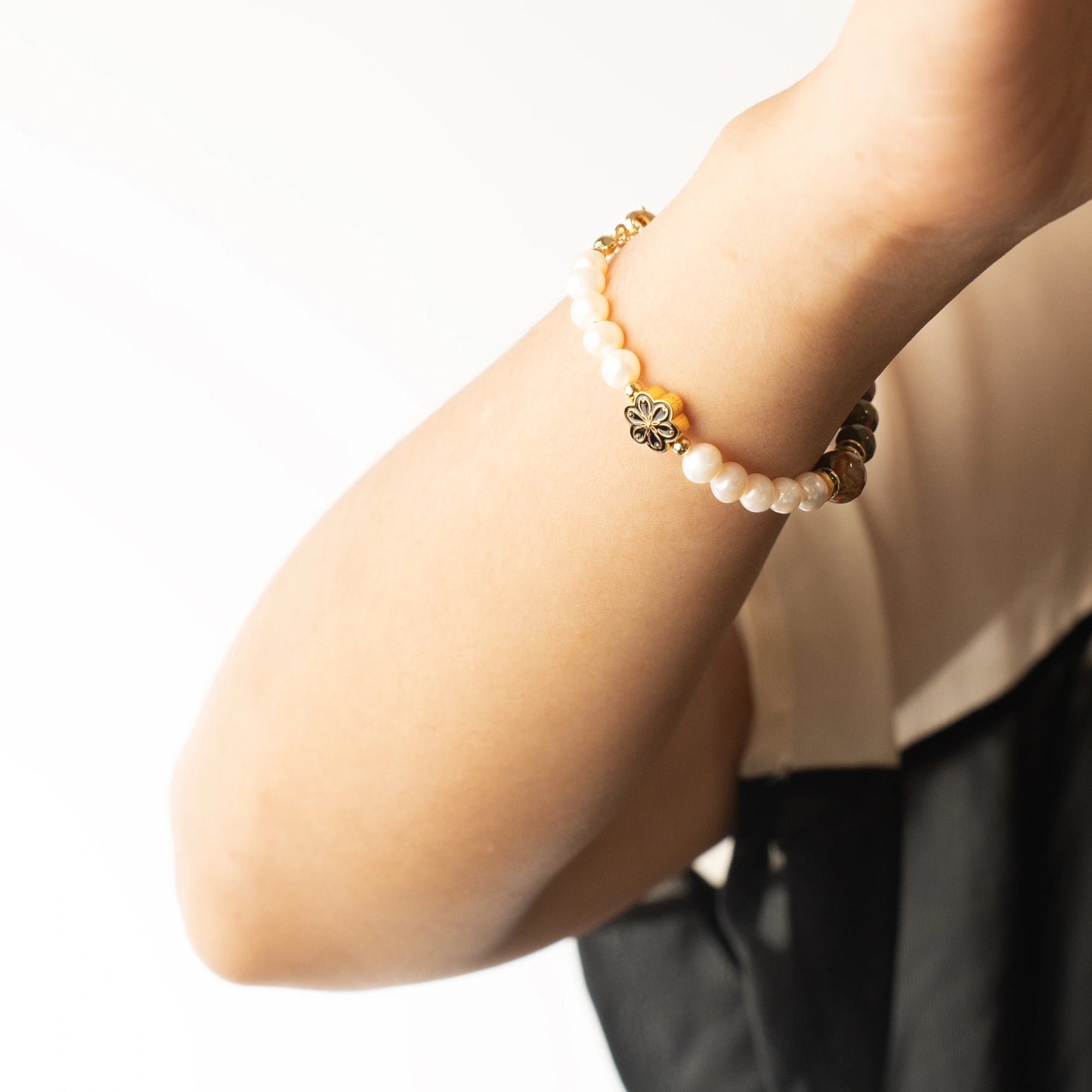 A person enjoying a moment of peaceful balance, wearing the Mulstio Unakite and Pearl bracelet as a gentle reminder for self-care and emotional grounding.