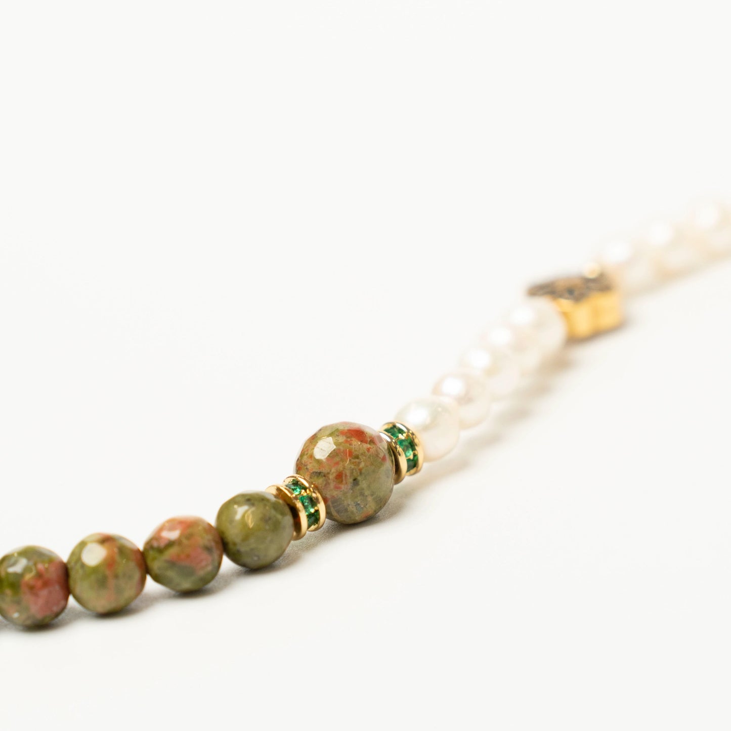 Close-up of the unique May birthday bracelet, showing the beautiful speckled green and pink pattern of the Unakite stone alongside the luminous white Pearl.