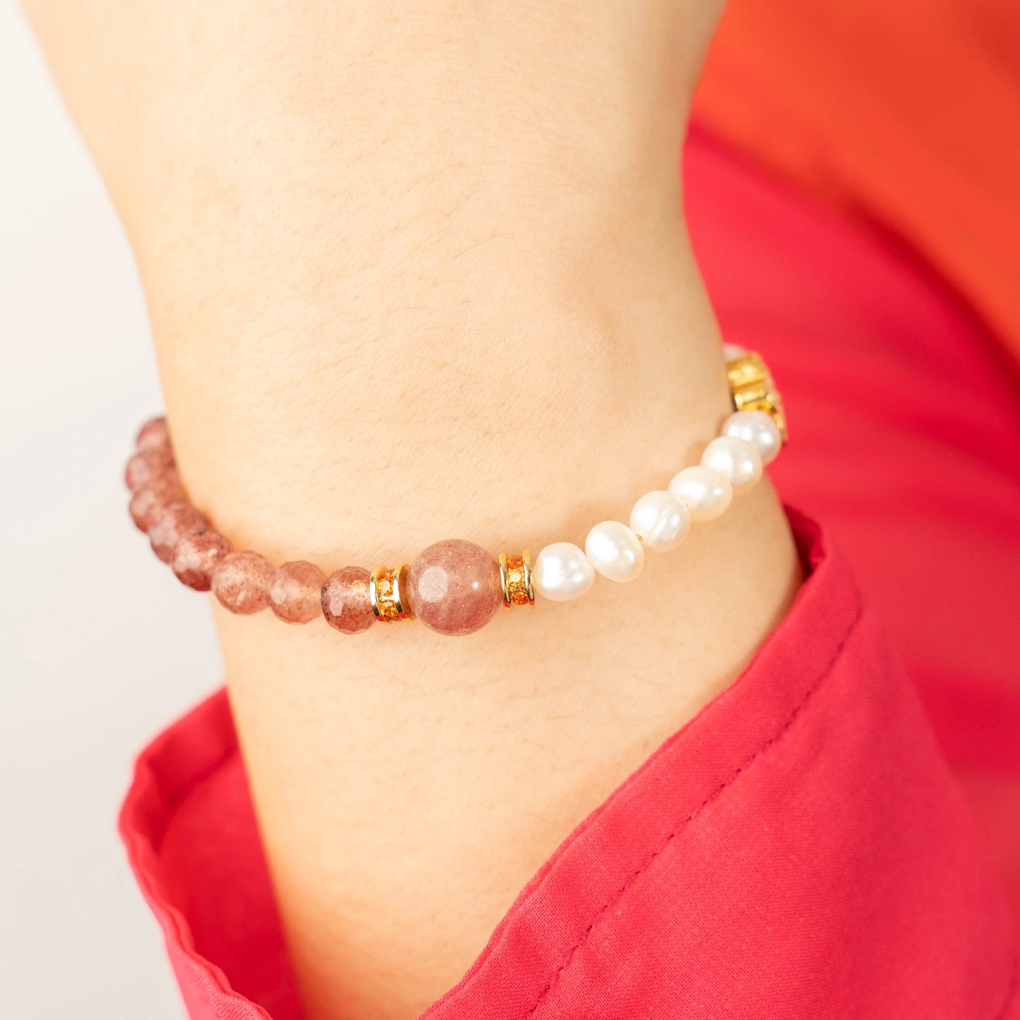 A person radiating positivity and a light heart, wearing the Mulstio Strawberry Quartz and Pearl bracelet as a symbol of their commitment to joyful living.