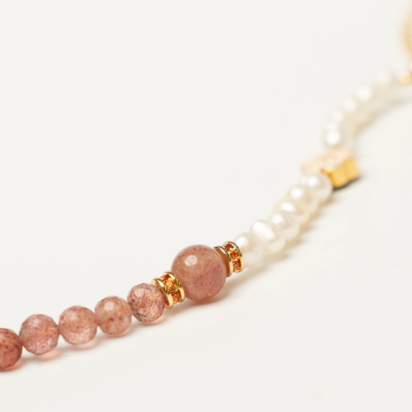 Close-up of the charming bracelet, showcasing the unique speckled pink and white pattern of the Strawberry Quartz beads alongside the soft, luminous glow of the Pearls.