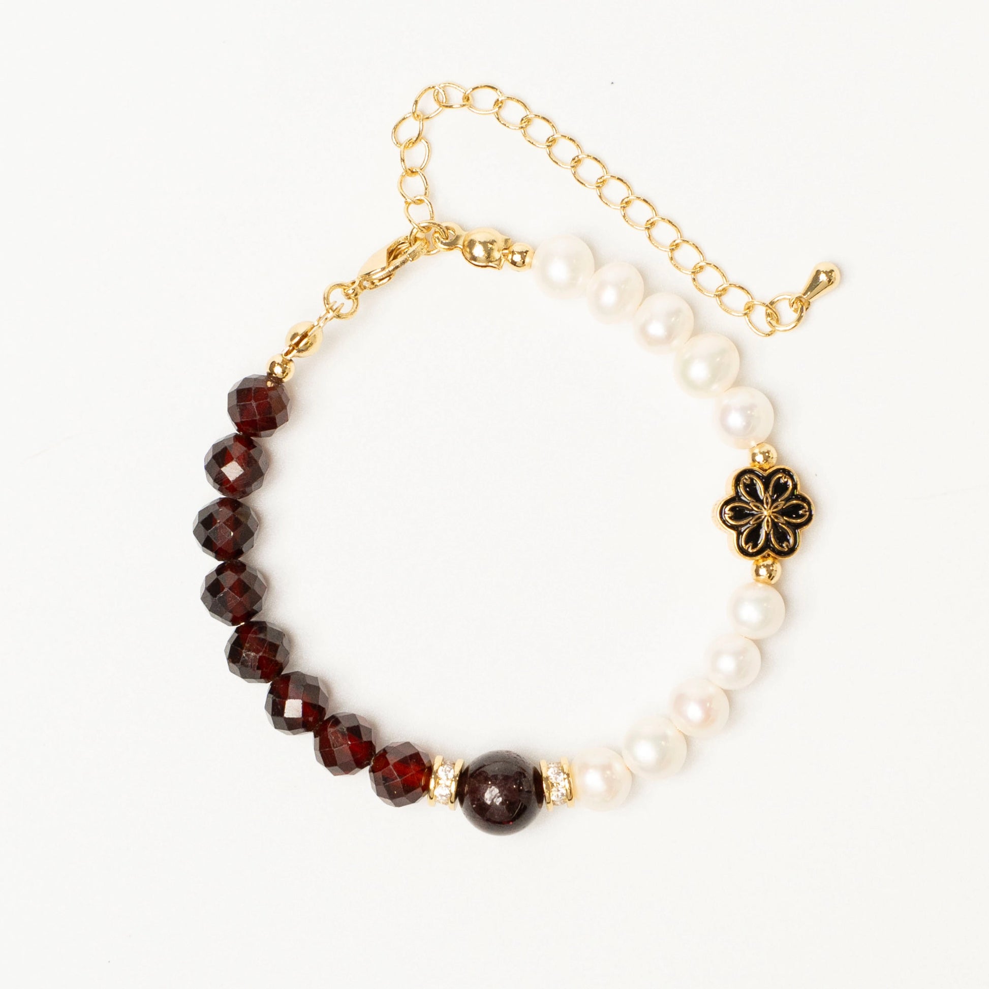 Close-up detail of the Mulstio bracelet showing the deep red garnet bead and smooth white pearl, hand-strung on a delicate gold-filled chain.